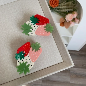 Detail view of colorful resin strawberry hair clips with green leaves for women