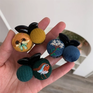 Close-up of handmade embroidered fabric mini hair claws featuring fox and bird patterns
