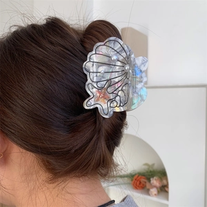 Detailed view of sea shell hair claw with pearls worn on hair from the back