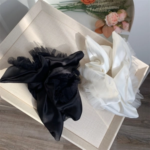 Detailed close-up of a satin and lace scrunchie set in black and creamy white colors