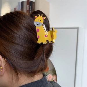 Detail view of a bright yellow giraffe acetate hair claw clip with purple spots
