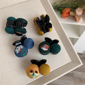 Detail view of various embroidered hair clips featuring birds and floral patterns