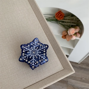 Gros plan d'une pince à cheveux flocon de neige bleu foncé avec strass sur un plateau