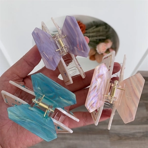 Macro detail of large acetate claw clips with marble texture and sparkling rhinestones