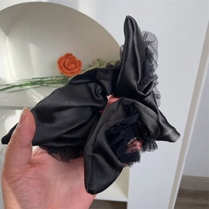 Close-up of black satin scrunchie with romantic lace mesh trim for elegant hairstyles