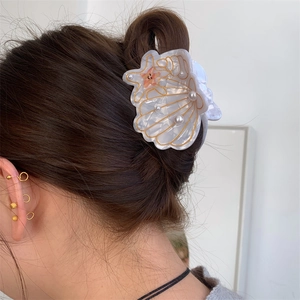 Detailed side view of a pearlescent white acetate seashell and starfish hair claw clip