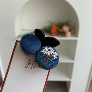 Creative embroidered hair clip featuring blue floral patterns and soft plush pompom decor