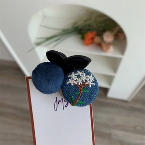 Detail of creative embroidery hair claw clip with plush ball and floral denim pattern