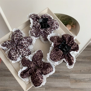Detail of four leopard print hair claws with white lace edges on a beige tray
