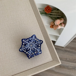 Détail de la pince à cheveux flocon bleue ornée de strass brillants sur tissu