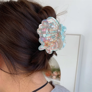 Detail of seashell hair claw with blue acetate finish, white pearls, and small starfish