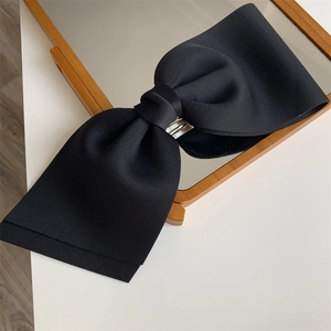 Detail of a large black bow hair clip featuring premium twill fabric and silver metal spring