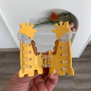 Detail of cute yellow cartoon giraffe hair claw clip with acetate finish and metal spring
