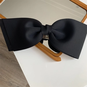 Close-up of a large black fabric bow hair clip featuring a sturdy silver metal spring clasp