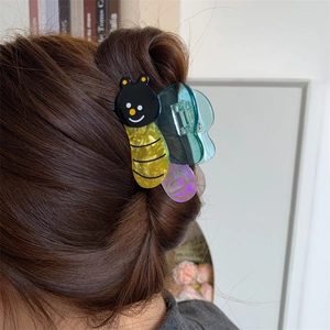 Detail showing an acetate butterfly hair claw clip worn on hair with a warm indoor background