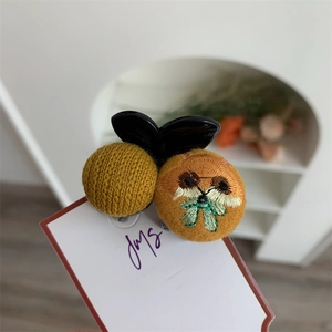 Close-up of yellow knit hair clip featuring a cute cat embroidery and acrylic bow