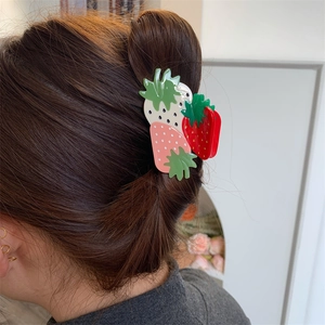 Close-up of a sweet strawberry hair claw clip worn on a messy bun for girls