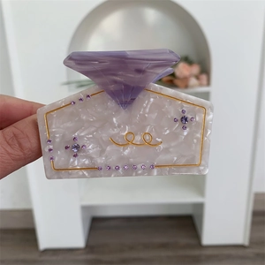 Detail of perfume bottle hair claw clip with purple rhinestones and marble texture