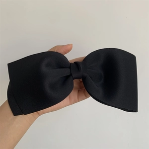 Close-up of black oversized bow hair clip with layered fabric texture and spring mechanism