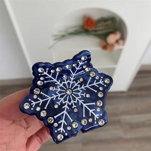 Gros plan d'une pince à cheveux flocon de neige bleue avec strass et texture marbrée