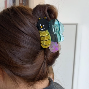 Detail showing a colorful cartoon bee hair claw clip on a model's brown hair bun