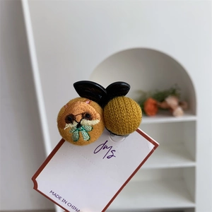 Detailed view of the yellow embroidered cat plush hair claw clip and knitted texture
