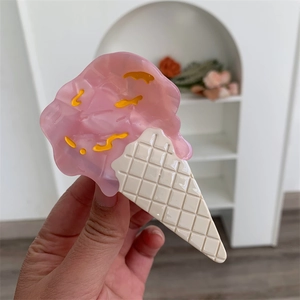 Detailed shot of an ice cream shaped hair claw clip made of pink and cream acetate material