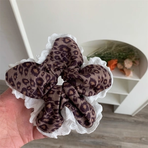 Close-up of leopard print hair scrunchie with delicate white lace trim and plush texture