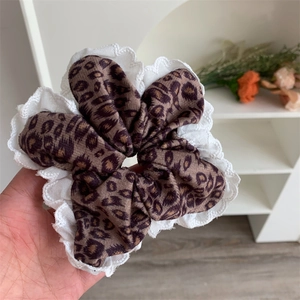 Detail of leopard print scrunchie featuring white lace edge and plush fabric texture