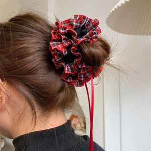 Detail of red plaid scrunchie with long ribbons worn on a low ponytail hair style