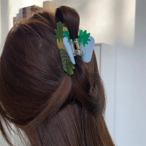 Close-up of strawberry fruit hair claw clip in green and pink on brunette hair