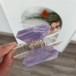 Detail of purple marble acetate hair claw clip with crystal accents and gold spring