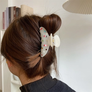 Dettaglio della pinza per capelli in acetato crema con Babbo Natale e cristalli colorati