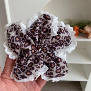 Detail of large leopard print scrunchie with white scalloped lace embroidery edges