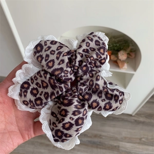 Close-up of leopard print scrunchie with white floral lace embroidery details