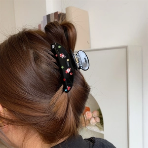 Dettaglio molletta natalizia con Babbo Natale e strass colorati su capelli scuri