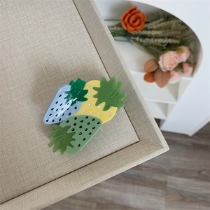 Detailed macro view of strawberry hair claw clips in blue, yellow, and mint green colors