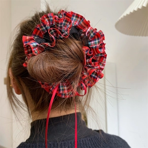Close-up of a large plaid hair scrunchie with red ribbons on a bun hairstyle
