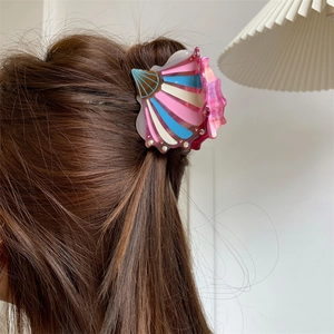 Detail view of shell hair claw with pink blue acetate stripes and crystal inlay