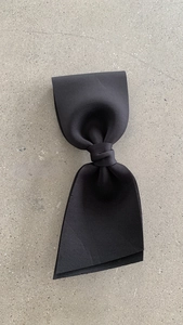 Macro detail of elegant black large bow hair clip crafted from thick textured fabric