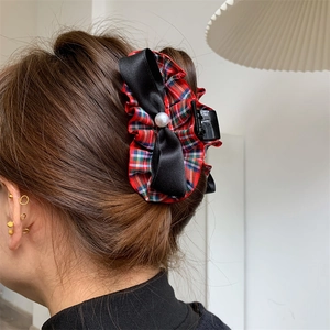 Detail of red plaid hair claw clip with black satin bow and a white faux pearl