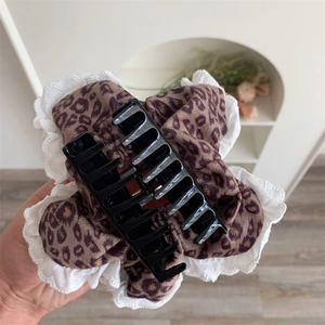 Detailed close-up of a leopard print claw clip with white lace trim and plush fabric