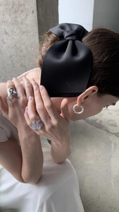 Detail view of large black matte silk bow hair clip on model with minimalist jewelry