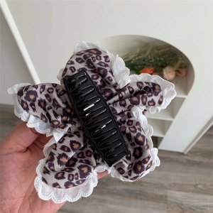 Detail showing elegant leopard print hair claw clip with white lace trim and fabric texture