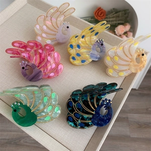 Close-up of peacock hair claws with marble texture acetate and golden outlines
