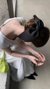 Elegant large black satin bow hair clip on model in a high-angle french minimalist style shot