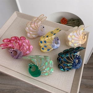 Close-up of colorful peacock hair claws in six vibrant pearlescent finishes with gold accents