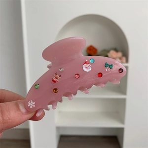 Dettaglio macro della pinza per capelli rosa opaco con renna festiva e strass colorati