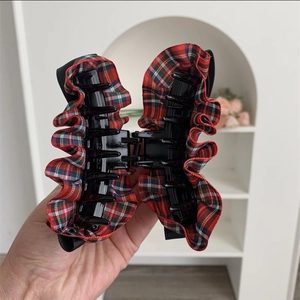 Detail of red and black plaid ruffled fabric on a large matte black hair claw clip