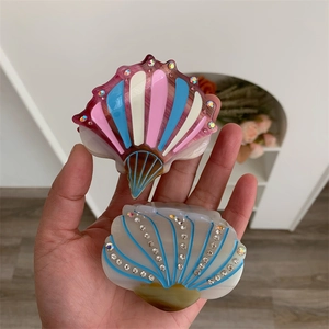 Detailed view of small shell hair claws with colorful stripes and sparkling rhinestones